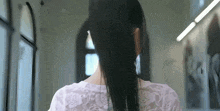 a woman with long black hair is wearing a white lace top and earrings .