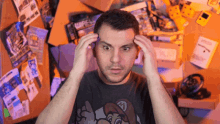 a man wearing a shirt with mario on it holds his hands to his head