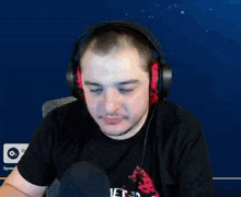 a man wearing headphones and a black shirt that says feed