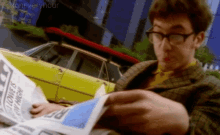 a man is reading a newspaper with a yellow car in the background and the words foxoneveryhour at the bottom