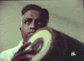 a man holds a drum in front of a screen that says " ish "