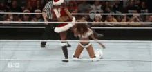a woman in a santa hat is wrestling another woman in a ring
