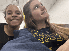 two women are posing for a picture and one has a shirt that says t2 on it