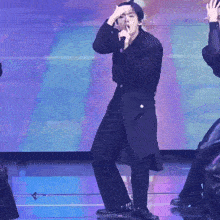a man is singing into a microphone while standing on a stage