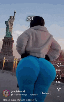 a picture of a woman standing in front of the statue of liberty with the caption " at please make statues bigger "