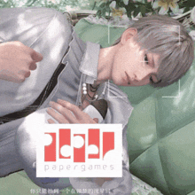 a man laying on a green couch with a papergames logo