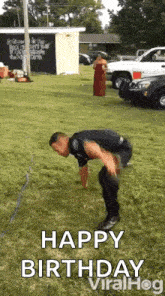 a man is bending over in the grass while a woman stands behind him .