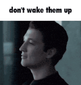 a man is standing in front of a window with the words `` don 't wake them up '' written on the bottom .