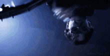 a man is hanging upside down in a dark room with a sword in his hand .