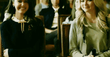 two women are sitting next to each other in a room and smiling