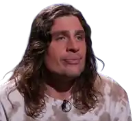 a man with long curly hair is wearing a tie dye shirt and a microphone .
