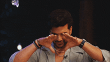 a man covering his eyes with his hands and a watch on his wrist