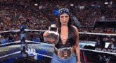 a woman in a wrestling ring holding a belt that says ' fuel ' on it