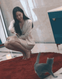 a woman in a white dress is playing with a cat