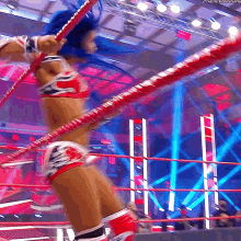 a woman with blue hair is jumping over a rope in a wrestling ring