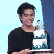 a man is holding a cake with a figurine on top of it and smiling .