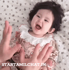 a baby is being held by a person with the website starttamilchat.in visible in the corner