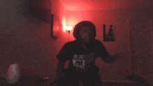 a man in a black shirt with chinese writing on it is standing in a dark room