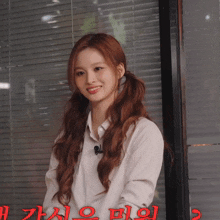 a woman with pigtails is smiling in front of a window with chinese writing