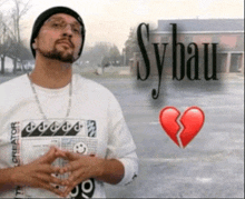 a man stands in front of a poster that says sybau and has a broken heart