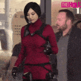 a woman in a red costume is walking in front of a sign that says the holly on it