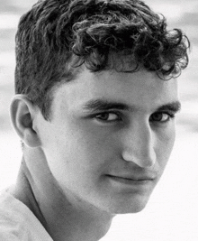 a young man with curly hair is looking at the camera in a black and white photo