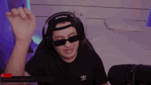 a man wearing sunglasses and headphones with the word adidas on his t-shirt