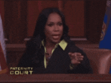 a woman wearing glasses stands in front of a paternity court sign