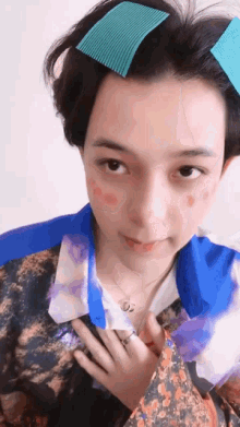 a woman with a ring on her finger is wearing a floral shirt and a blue jacket