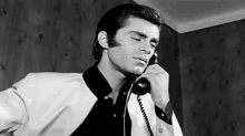 a man is talking on a telephone with his eyes closed