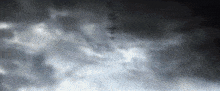 a dark cloudy sky with a few trees in the distance