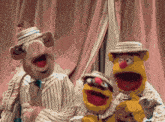 three muppets wearing suits and hats are standing next to each other on a stage