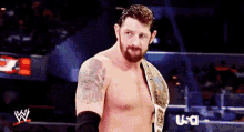a shirtless wrestler is standing in a wrestling ring with a usa logo in the background
