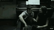 a man and a woman are kneeling down in front of a piano with a rbd.gif written below them