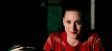 a woman is wearing a red sweater and giving a thumbs up .