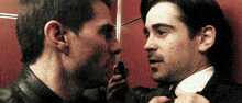 a man holding a gun talks to another man in a suit