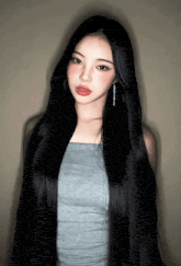 a woman with very long black hair is wearing a grey top