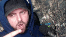 a man wearing a ny hat and a blue hoodie is talking into a microphone