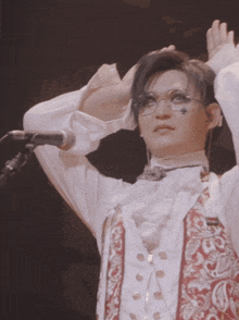 a man wearing glasses and a red and white vest stands in front of a microphone