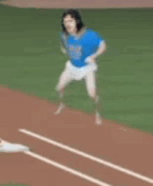 a baseball player in a blue shirt and white shorts is standing on a base .