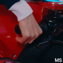 a close up of a person 's hand holding a steering wheel with the letters ms above it