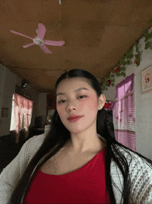 a woman taking a selfie in front of a pink fan