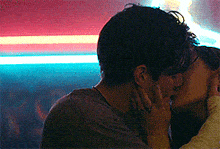 a man and a woman kissing in front of a neon sign