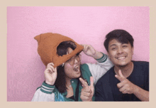 a man and a woman are posing for a picture with a pink background