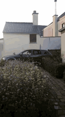 a car is parked in front of a house with a chimney on the roof
