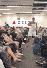a man in a white tank top is running in front of a delta sign