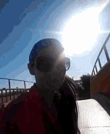 a person wearing sunglasses and a hat is standing in front of a blue sky