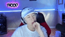 a person wearing headphones and a hat is sitting in a chair in front of a neon sign .
