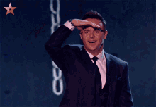 a man in a suit and tie is smiling and covering his eyes