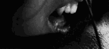a black and white photo of a person 's mouth eating a piece of cocaine .